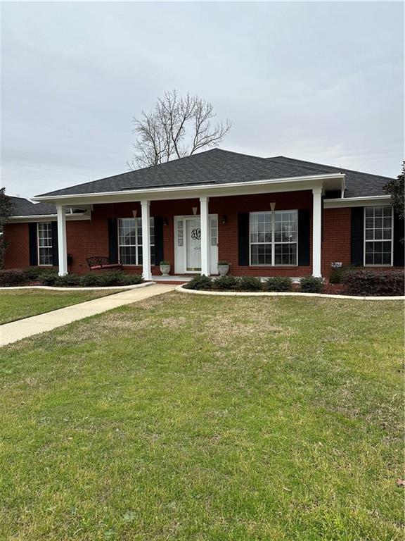 view of front of property featuring a front yard, brick siding, and roof with shingles