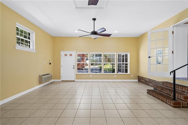 interior space with a wall unit AC, ceiling fan, baseboards, and light tile patterned flooring