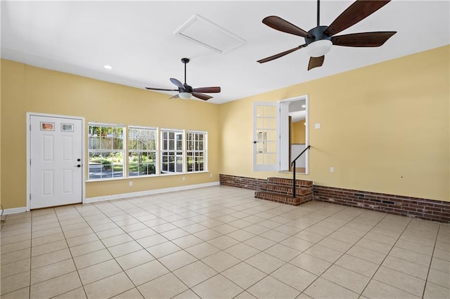 unfurnished room featuring light tile patterned floors, attic access, brick wall, and baseboards