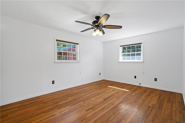 unfurnished room with wood-type flooring, a healthy amount of sunlight, and baseboards