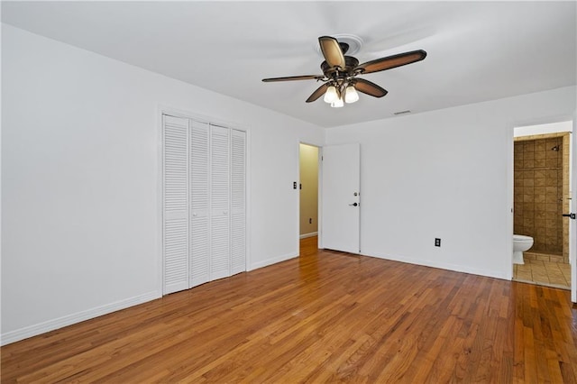 unfurnished bedroom featuring a closet, visible vents, light wood-style flooring, ensuite bath, and baseboards