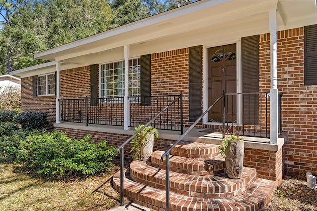 doorway to property with covered porch and brick siding