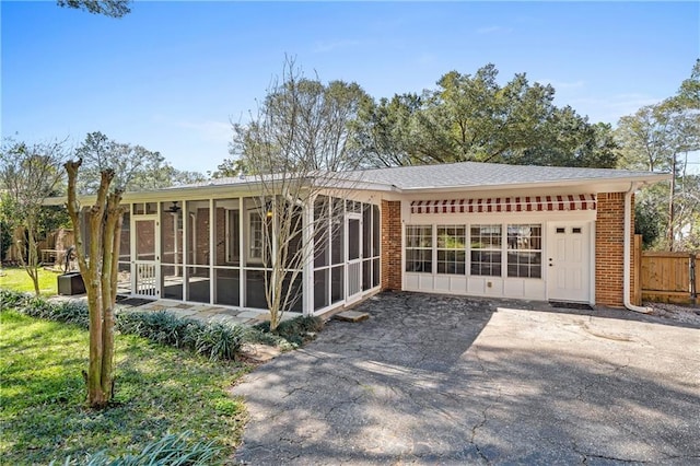 rear view of property with brick siding, fence, and a sunroom