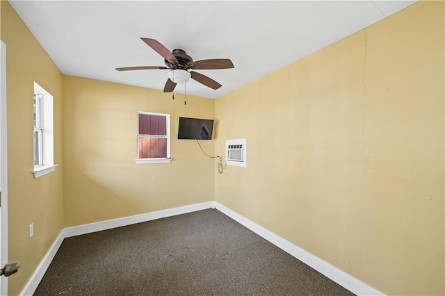 empty room with a ceiling fan, baseboards, dark colored carpet, and an AC wall unit