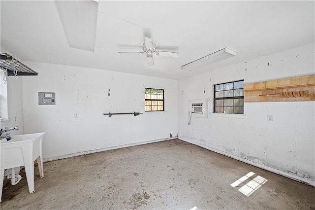 empty room with a ceiling fan, a sink, concrete flooring, a wall mounted air conditioner, and electric panel