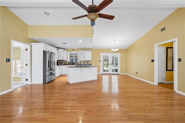 kitchen featuring stainless steel appliances, white cabinets, vaulted ceiling, open floor plan, and french doors