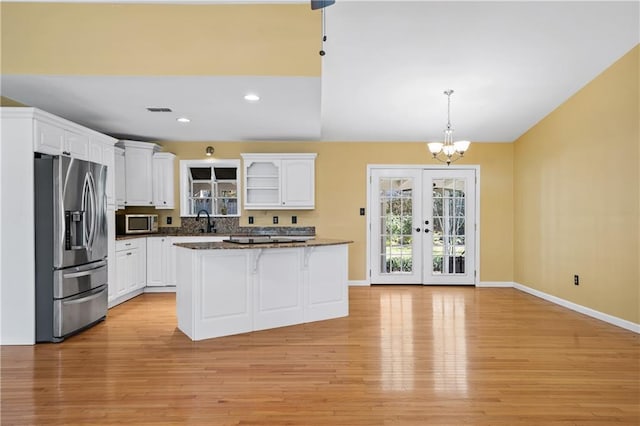 kitchen featuring white cabinets, a breakfast bar area, stainless steel appliances, french doors, and light wood-type flooring