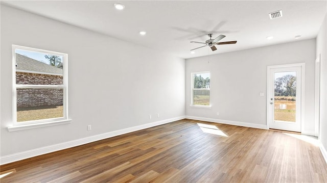 spare room with baseboards, plenty of natural light, a ceiling fan, and wood finished floors
