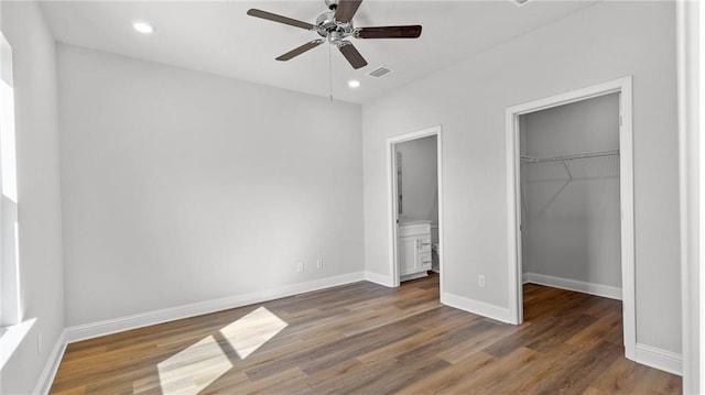 unfurnished bedroom with visible vents, a closet, wood finished floors, baseboards, and a spacious closet