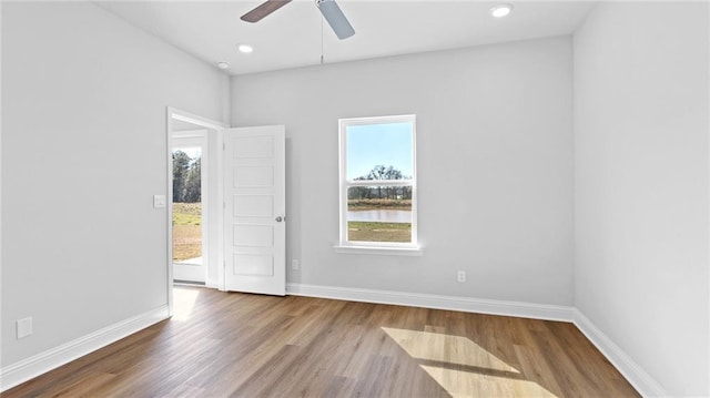 unfurnished room featuring baseboards, ceiling fan, a healthy amount of sunlight, and wood finished floors