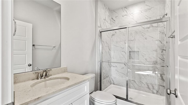 bathroom featuring vanity, a shower stall, and toilet