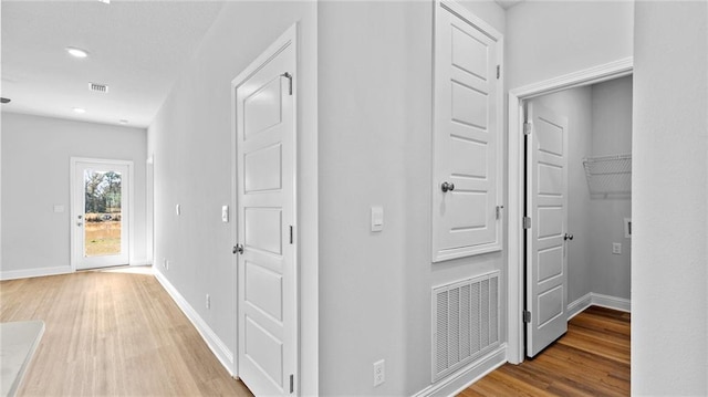 corridor with visible vents, baseboards, and wood finished floors