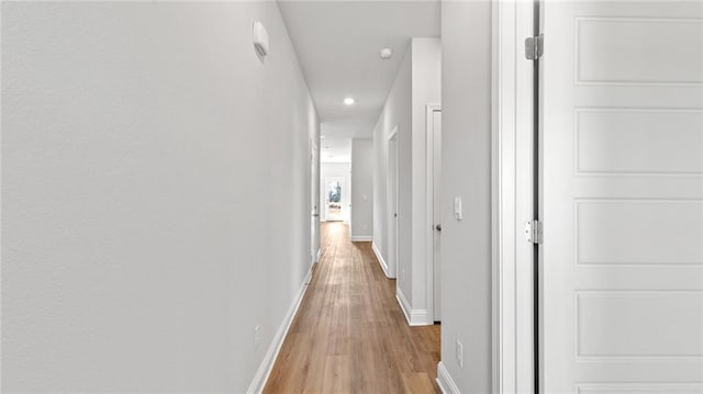 corridor featuring baseboards, light wood-type flooring, and recessed lighting