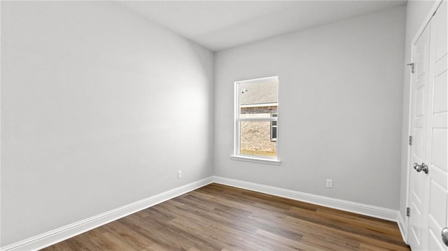 spare room with baseboards and dark wood-style flooring
