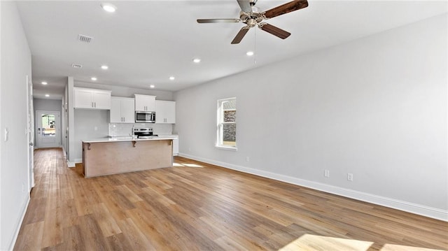 kitchen with plenty of natural light, appliances with stainless steel finishes, baseboards, open floor plan, and recessed lighting