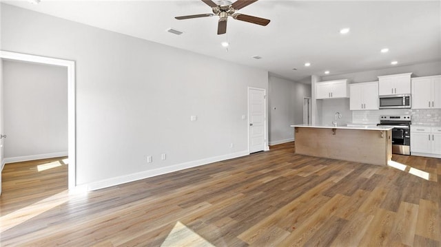 kitchen featuring decorative backsplash, a ceiling fan, light wood-style floors, stainless steel appliances, and recessed lighting