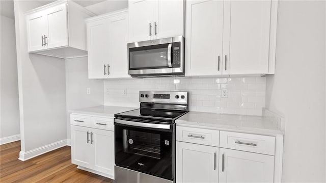 kitchen featuring baseboards, light wood-type flooring, backsplash, and stainless steel appliances