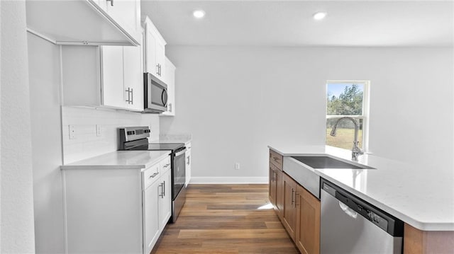 kitchen featuring appliances with stainless steel finishes, dark wood finished floors, a sink, recessed lighting, and an island with sink