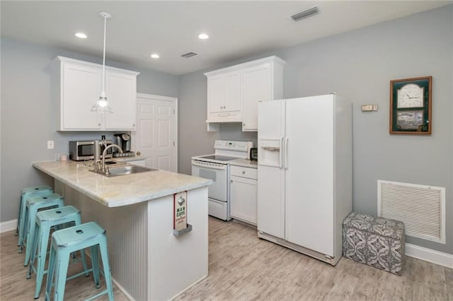 9102 Magnolia Ct, Spanish Fort, AL 36527 - kitchen featuring white appliances, a sink, light wood-style floors, a peninsula, and a kitchen bar