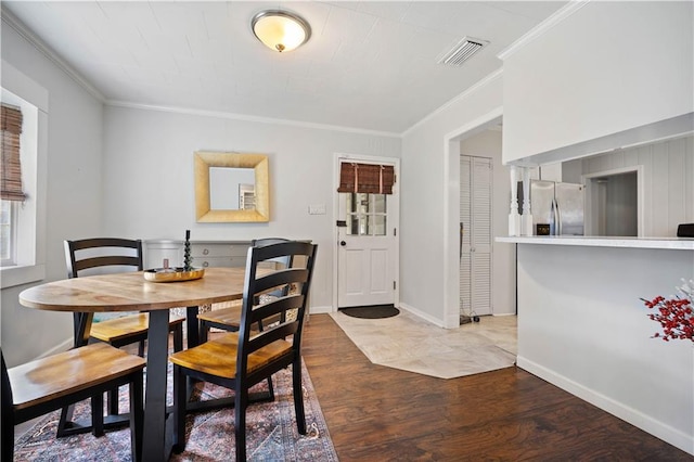 dining room with crown molding, light wood-style floors, and baseboards