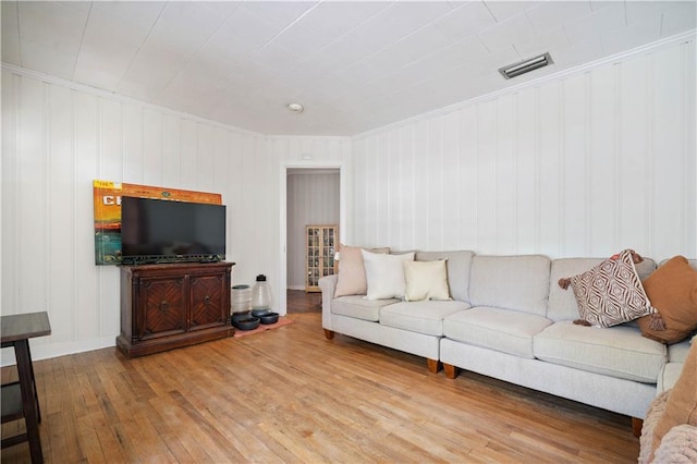 living area with hardwood / wood-style floors, crown molding, and baseboards