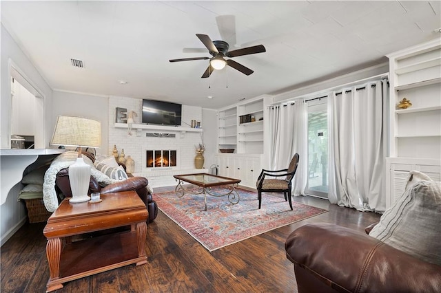living area featuring a ceiling fan, wood finished floors, a fireplace, and built in features