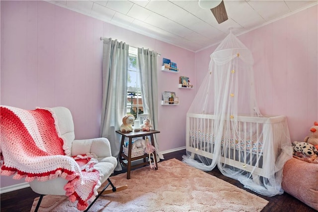 bedroom featuring wood finished floors, ornamental molding, baseboards, and a ceiling fan