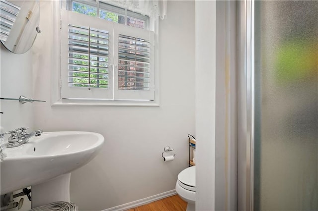 bathroom featuring toilet, wood finished floors, baseboards, and a sink