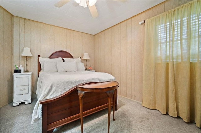 carpeted bedroom featuring wooden walls and a ceiling fan