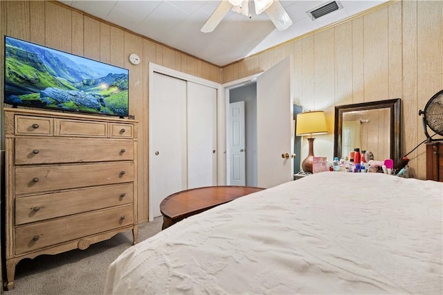 bedroom featuring carpet, wooden walls, a ceiling fan, a closet, and vaulted ceiling
