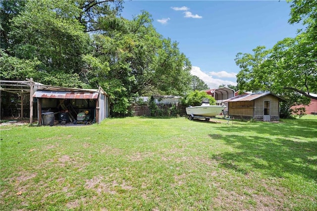 view of green lawn with a detached carport and an outbuilding