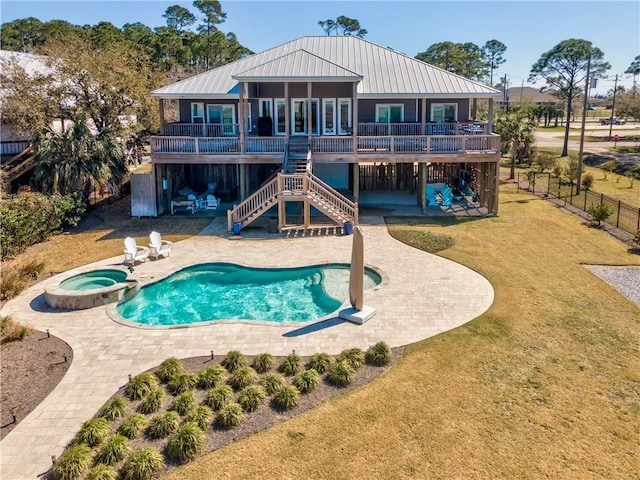 rear view of property with a yard, a patio, a pool with connected hot tub, stairway, and a fenced backyard