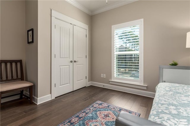 bedroom featuring a closet, dark wood-style flooring, crown molding, and baseboards