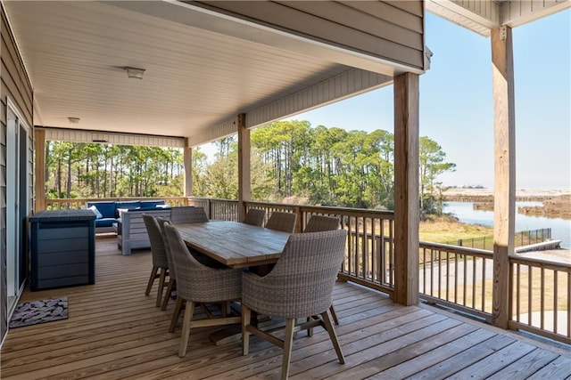 wooden terrace featuring outdoor dining area, a water view, and an outdoor living space