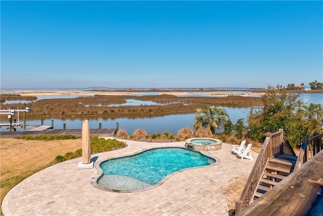 view of swimming pool with a pool with connected hot tub, a water view, and a patio