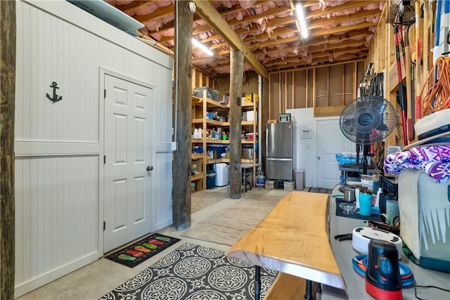 unfinished basement featuring freestanding refrigerator