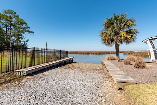 exterior space featuring a water view, fence, and a boat dock