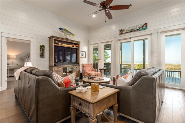 living area with ceiling fan, ornamental molding, and wood finished floors