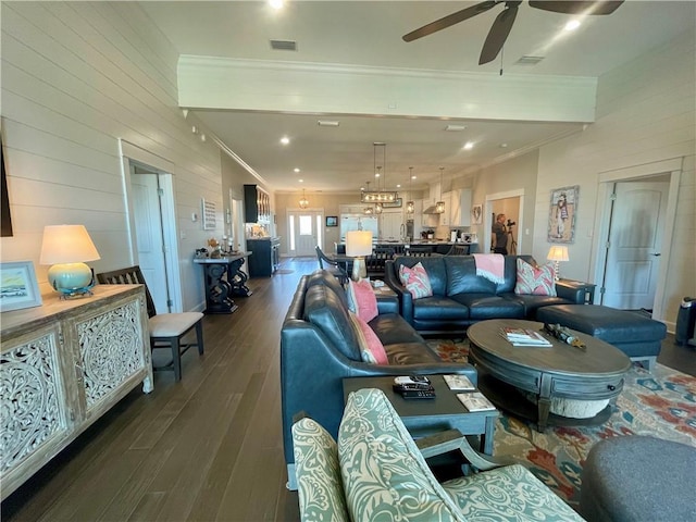 living room featuring ceiling fan, dark wood finished floors, visible vents, and crown molding