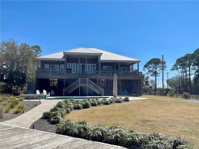 back of property with stairs, a yard, metal roof, and an outdoor pool