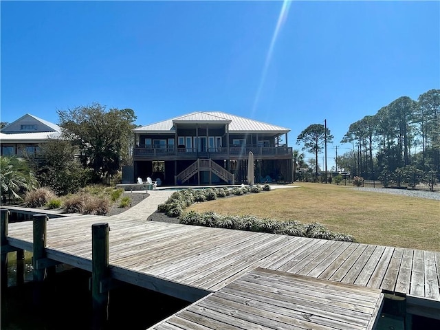 back of property featuring a standing seam roof, stairs, metal roof, and a yard