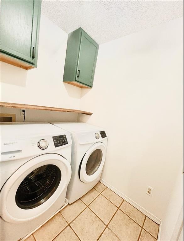 laundry room with light tile patterned flooring, a textured ceiling, cabinets, and separate washer and dryer