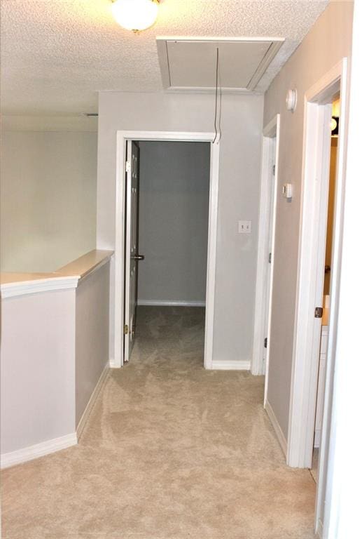 corridor with a textured ceiling and light colored carpet