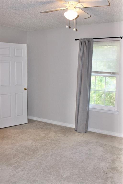 carpeted spare room featuring ceiling fan and a textured ceiling