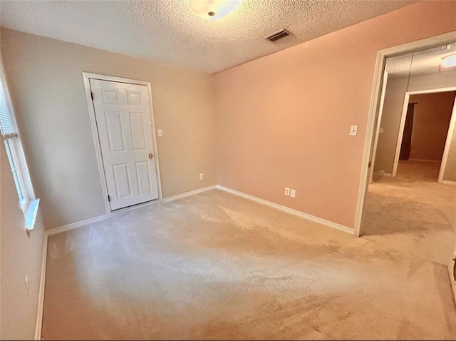 unfurnished room featuring a textured ceiling and carpet