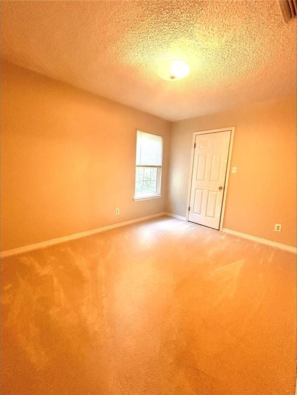 unfurnished room with a textured ceiling and carpet flooring