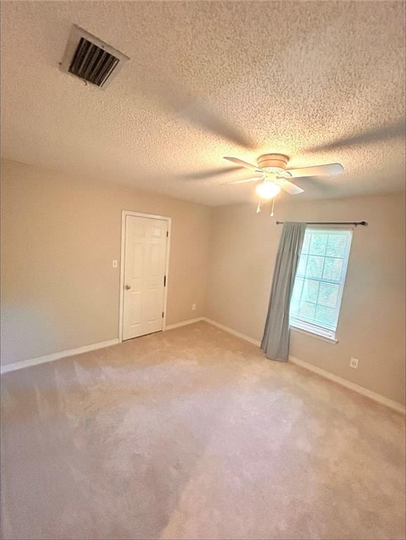 carpeted spare room featuring ceiling fan and a textured ceiling