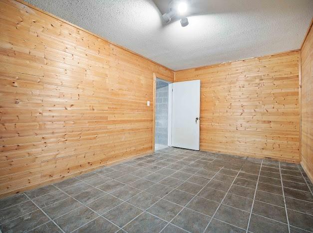 empty room with a textured ceiling and wood walls