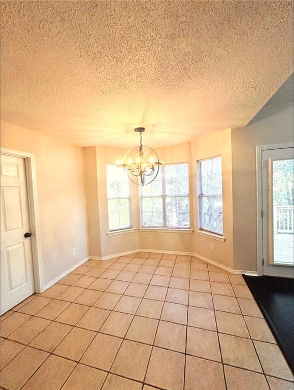 unfurnished dining area with a chandelier, light tile patterned flooring, and a textured ceiling