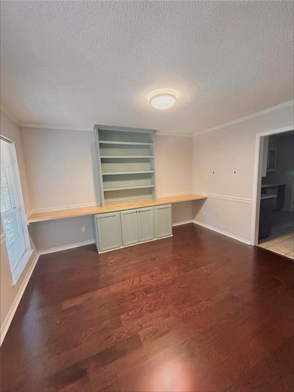 spare room with built in desk, a textured ceiling, and wood-type flooring